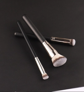 Three premium makeup brushes with black matte handles and gradient synthetic bristles