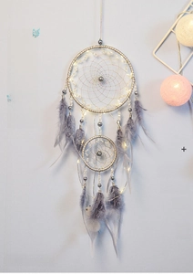 Detail of grey dream catcher with warm LED fairy lights and soft purple feathers
