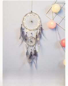 Close-up of handmade grey dream catcher with soft feathers and warm LED light decoration