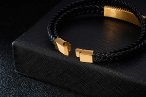 Macro detail of black braided leather bracelet with golden magnetic closure on gift box