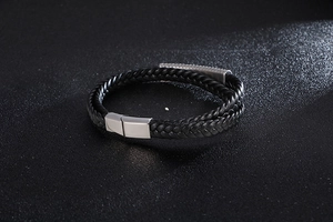 Detail of a double-strand black braided leather bracelet with a silver stainless steel clasp