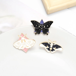 Trois broches en émail papillon et papillon de nuit sur une assiette en céramique