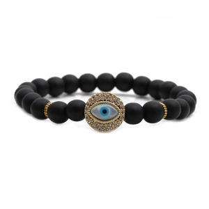 Black matte 8mm beaded bracelet featuring a gold Evil Eye charm with blue accents