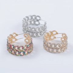 Macro detail of three chain-link hoop earrings in gold, silver, and multicolor stones
