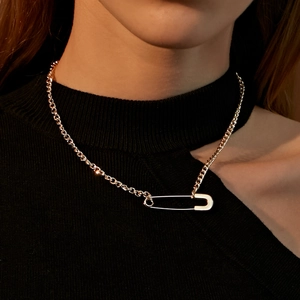 Detail of creative golden paperclip necklace pendant on black turtleneck sweater