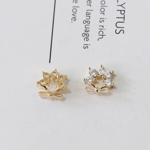 Macro di gioielli per unghie a fiore dorato con zirconi e fiocco su carta bianca