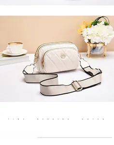 Detail of white quilted crossbody bag with dual zippers and heart-shaped metal logo