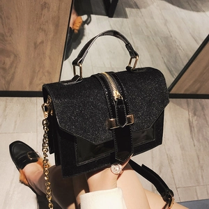 Sparkly black crossbody bag with gold handle and chain strap worn by a model