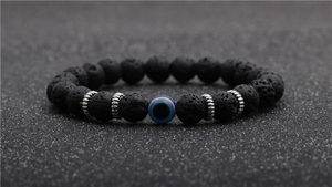 Macro shot of black lava stone beads with a blue evil eye bead and silver spacers