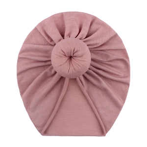 Pink cotton blend baby donut turban hat with top knot detail on a white background