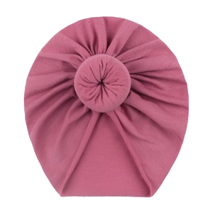 Detailed view of pink knitted baby donut hat with soft ribbed texture and top knot design