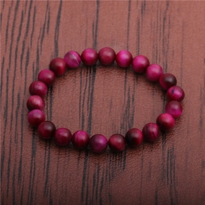 Detailed view of 8mm magenta tiger eye beaded bracelet on a dark wooden background
