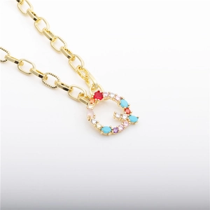 Detail of gold letter Q necklace with inlaid colorful gemstones and turquoise setting