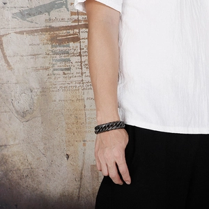Close-up of a masculine dark stainless steel curb chain bracelet on a male wrist