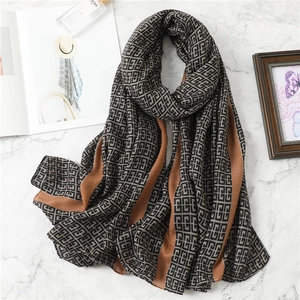 Flat lay of geometric pattern scarf in grey and brown on white marble background