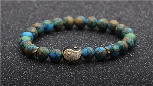 Detailed macro view of an 8mm natural stone bead bracelet featuring a gold Yin Yang charm
