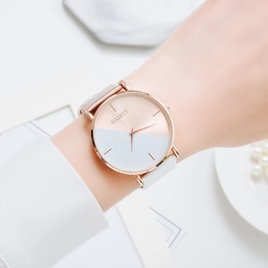 Minimalist bicolor rose gold and white quartz watch on wrist with elegant pearl accessories