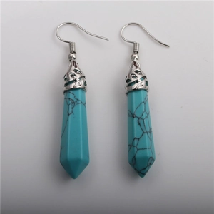 Detail of silver drop earrings with turquoise-colored hexagonal stone and hollow cap