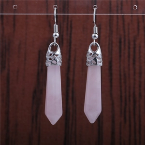 Macro detail of hexagonal pink crystal earrings with silver hooks on wood background