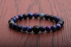 Close-up of blue and purple tiger eye stone beaded bracelet on a dark wooden background