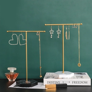 Golden T-bar jewelry stands with black and white marble bases for earrings and necklaces