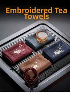Detailed close-up of embroidered linen tea towels with plum blossom patterns on tea tray