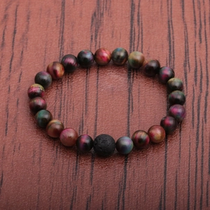 Handmade beaded bracelet featuring tiger eye stones and a black lava stone on wood background