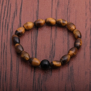 Handcrafted tiger eye stone bracelet with brown olive beads on a dark wood background