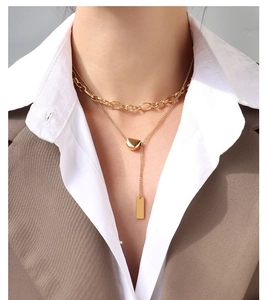 Detailed view of layered gold double-strand necklace with bar pendants on a model