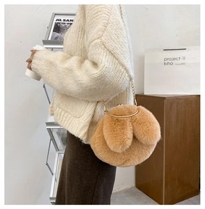 Detail of cute khaki plush rabbit bag with gold metal chain strap on model shoulder
