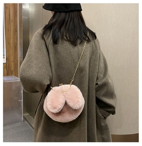 Detailed view of pink plush bunny bag with metal chain strap on model's shoulder