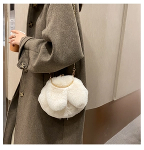 Close-up of fluffy white faux fur rabbit bag with gold metal frame and chain strap