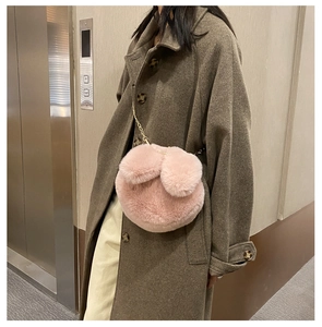 Detailed view of pink plush rabbit ear crossbody bag with gold chain strap on model