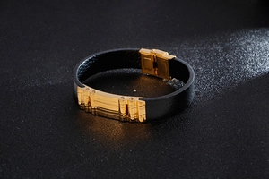 Dettaglio del bracciale in pelle nera intrecciata con fibbia in acciaio inossidabile dorato