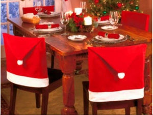 Detail view of two red and white plush Santa hat chair covers in a festive dining room