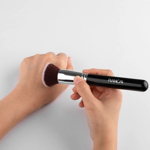 Detailed view of dense synthetic bristles applying foundation on skin with a black makeup brush