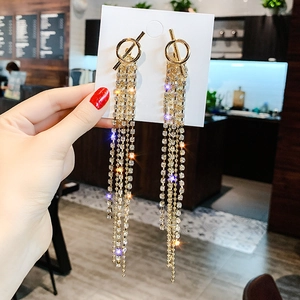 Close-up of golden tassel earrings with sparkling rhinestones on display card