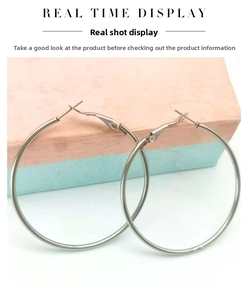 Detailed view of silver stainless steel large hoop earrings on a decorative gift box