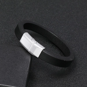 Close-up of black leather bracelet with a polished silver magnetic clasp on a textured base