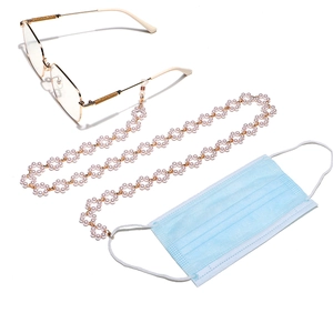 Chaîne à lunettes et cordon de masque en perles blanches avec fermoirs dorés sur fond blanc