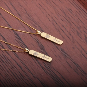 Collane con pendente rettangolare dorato con cuore e croce in zirconi su sfondo legno
