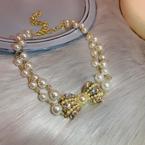 Double-layer pearl necklace with a rhinestone bow pendant on a grey plush background