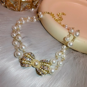 Macro shot of a golden crystal bow pendant on an elegant double-layered pearl necklace