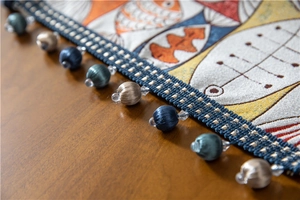 Detail of chenille table runner with fish pattern and colorful decorative tassels
