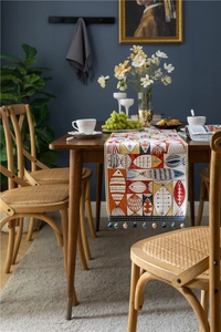 Detail of chenille table runner featuring colorful fish patterns and blue beaded tassels