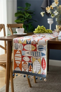 Detail of chenille table runner with fish patterns and decorative blue bead tassels