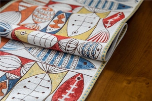 Macro shot of chenille table runner featuring festive fish patterns and woven textures
