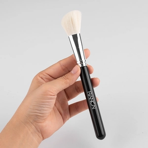 Angled contour makeup brush with soft bristles and black handle held by hand