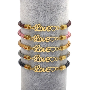 Close-up of woven leather bracelets with gold Love lettering and heart charms on display