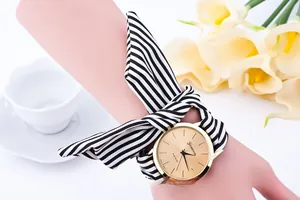Close-up of Geneva women's watch with golden dial and black-white striped fabric strap
